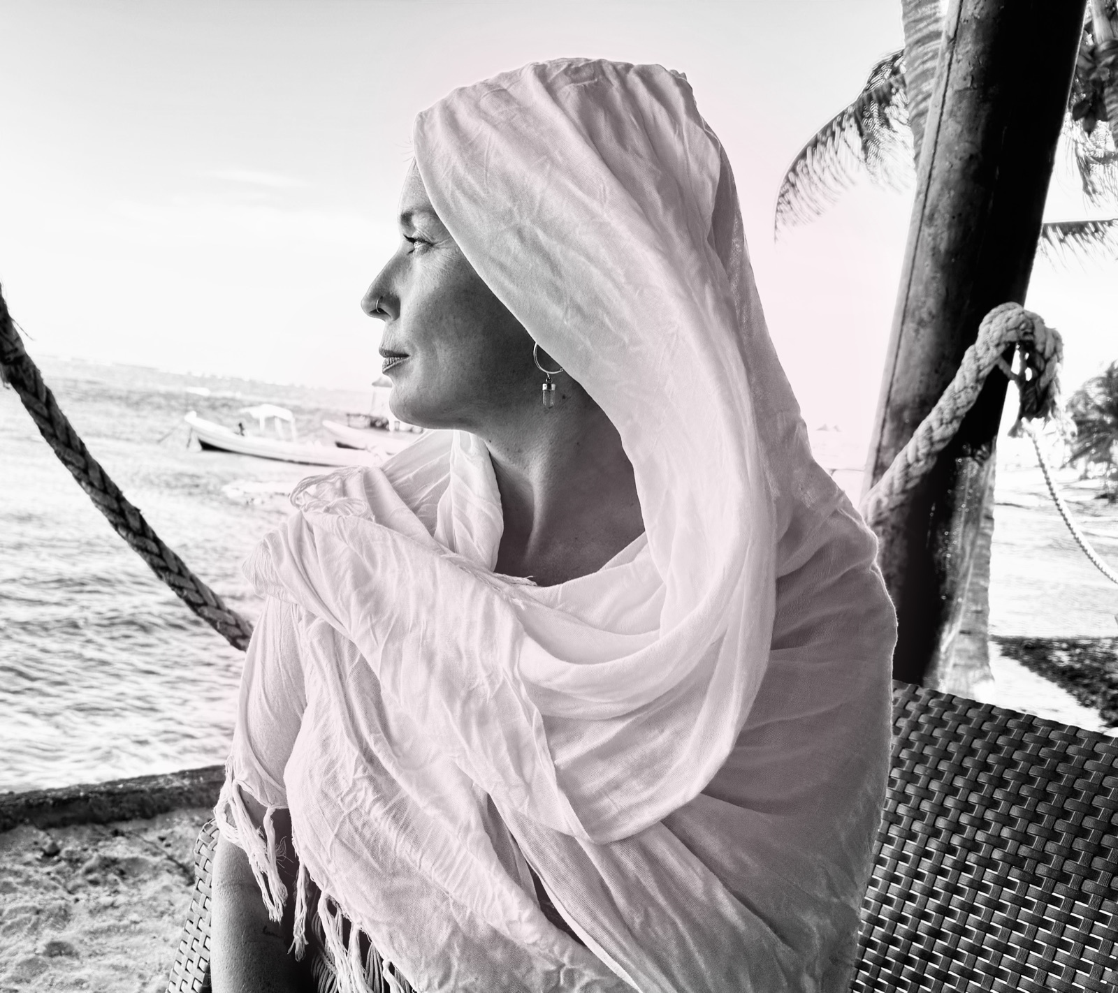 Mama Blue wrapped in a white shawl, looking out at the beach in Tulum